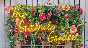 The Grounds of Alexandria neon sign and flowers around window