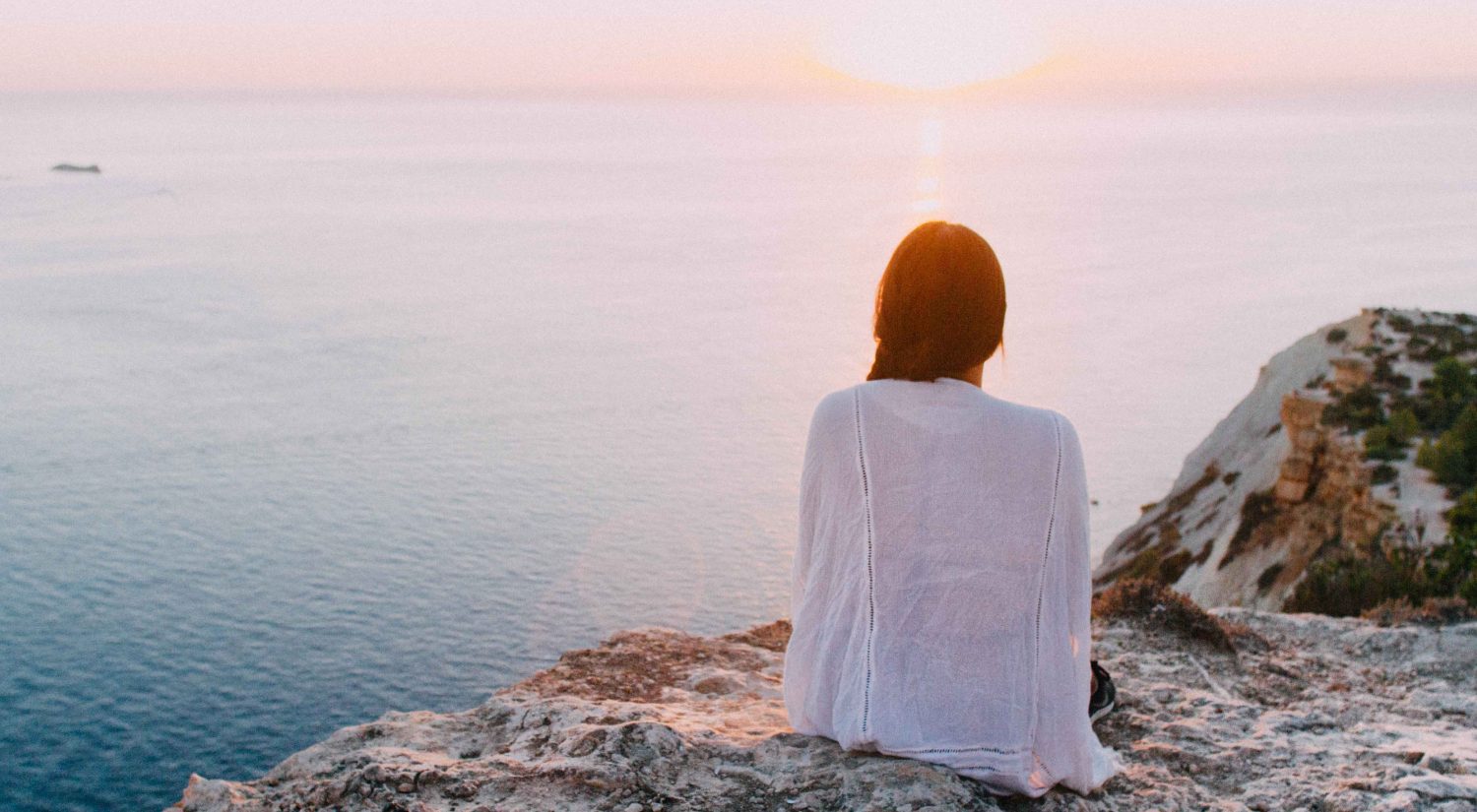 Woman sitting on cliff looking over ocean, Jacinta Ardern, mama disrupt