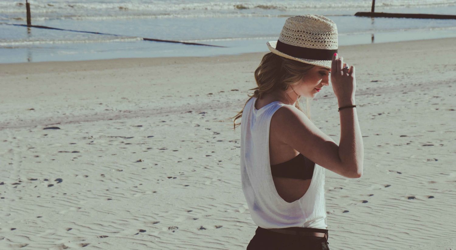 Woman walking on beach wearing hat