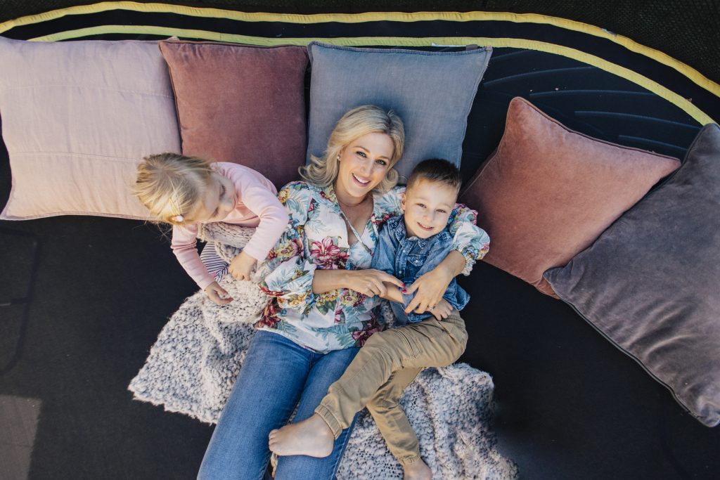 Mum relaxing on trampoline with children