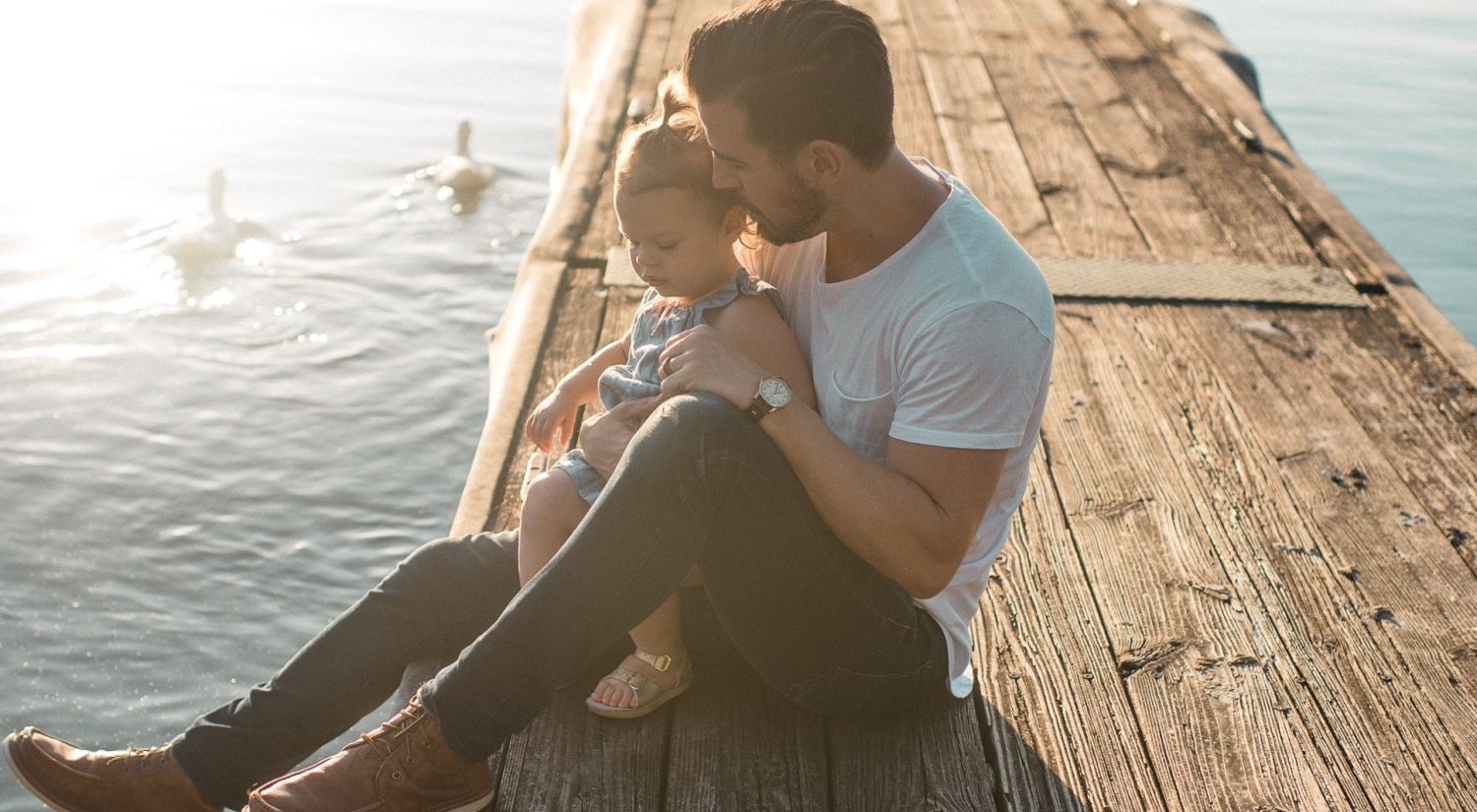 Father and daughter sitting on jetty