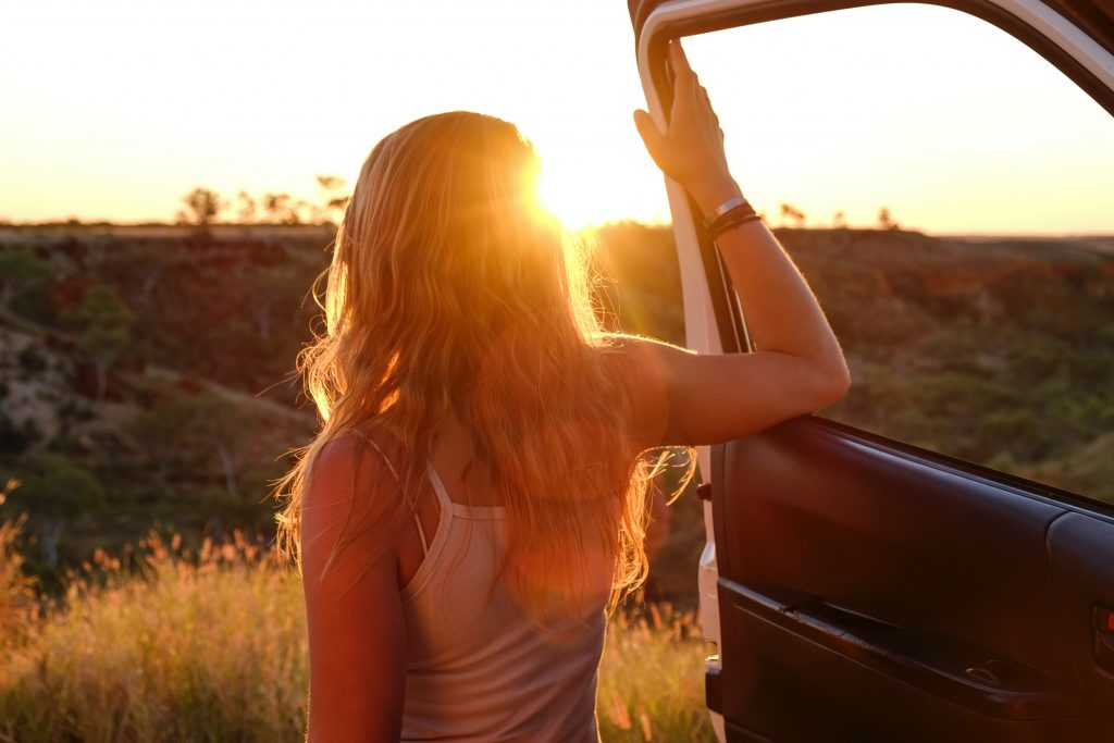 Woman on road trip standing next to car