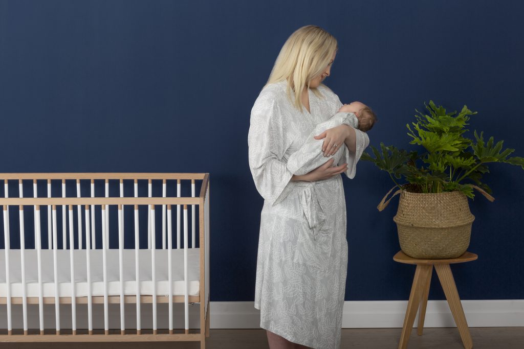Mum holding baby in nursery weraing ergopouch matchy matchy robe