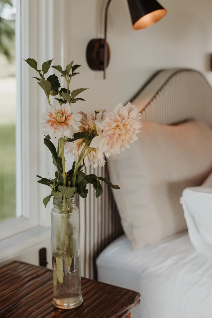 The Gatehouse exterior with purple flowers blooming along the white weatherboard cottage