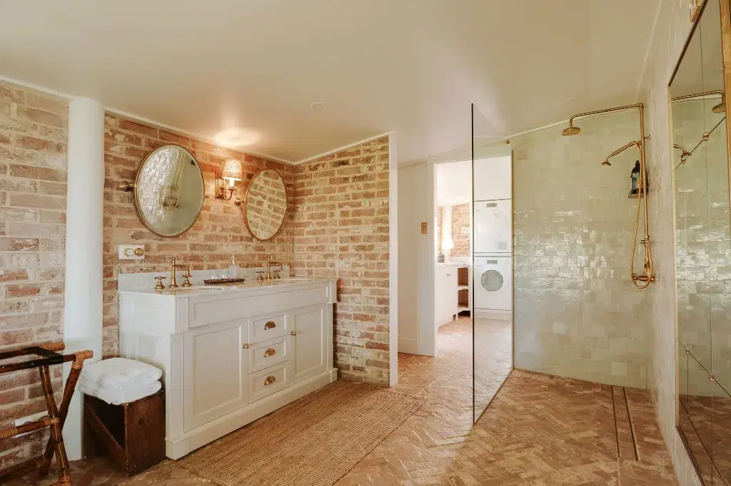The Gatehouse bathroom with marble vanity, exposed brick and walk-in shower